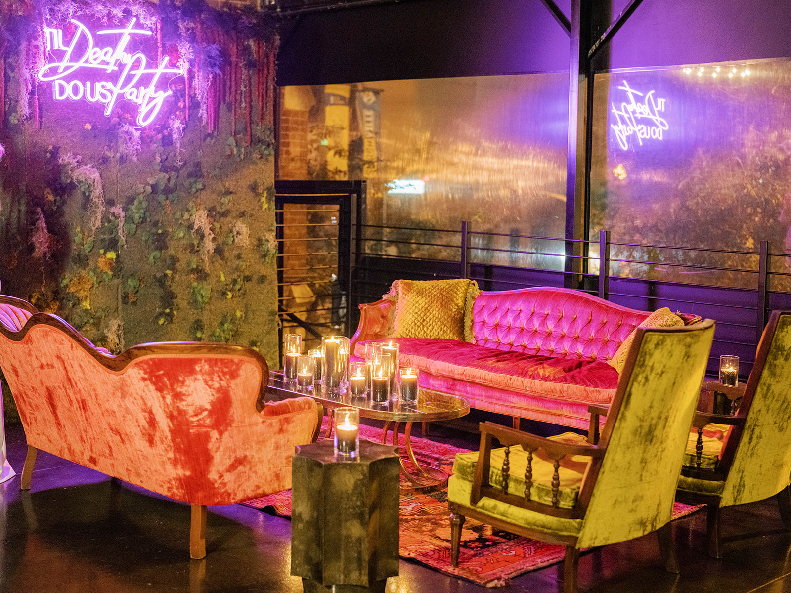 Wedding reception lounge setup with velvet furniture, oriental rug, and pink custom neon sign