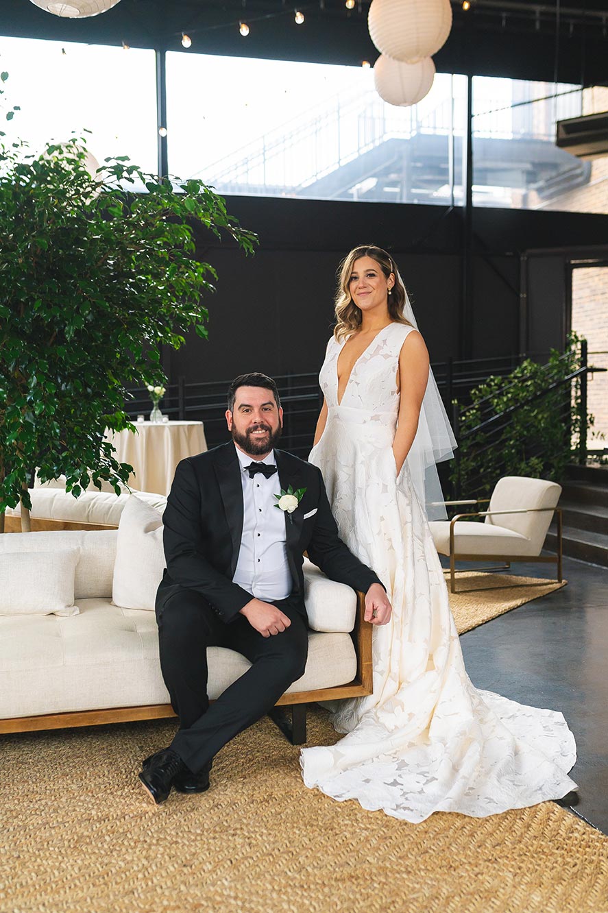 Bride and groom pose for portrait on Bell Tower patio set up with lounge furniture
