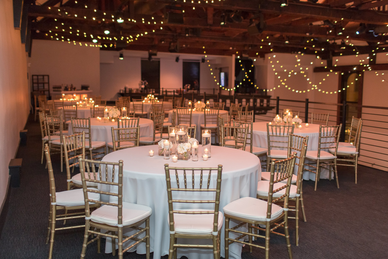 Wedding reception table setup on mezzanine with gold chiavari chairs and classic white table linens