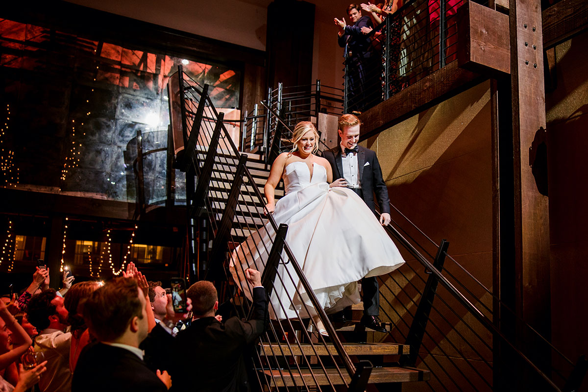 Bride and groom enter reception down mezzanine staircase