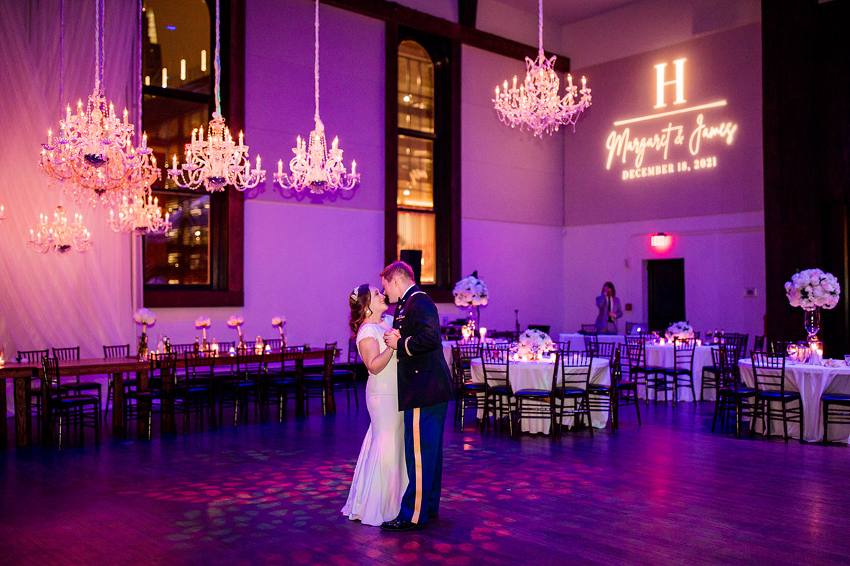 Bride and groom last dance in the main space with purple color wash and several chandeliers