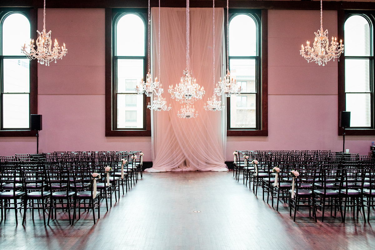 Wedding ceremony setup with romantic drapery and multiple chandeliers