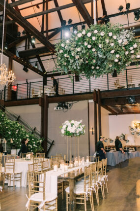greenery filled reception with white florals and hanging installations